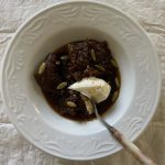 ayote en miel (pumpkin in syrup) topped with marscapone, pepitas, and clementine zest. there is a spoon digging into the mixture on the bottom-right side of the picture.