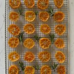 candied mandarins, decorated with rosemary sprigs, set on top of a cooling rack.