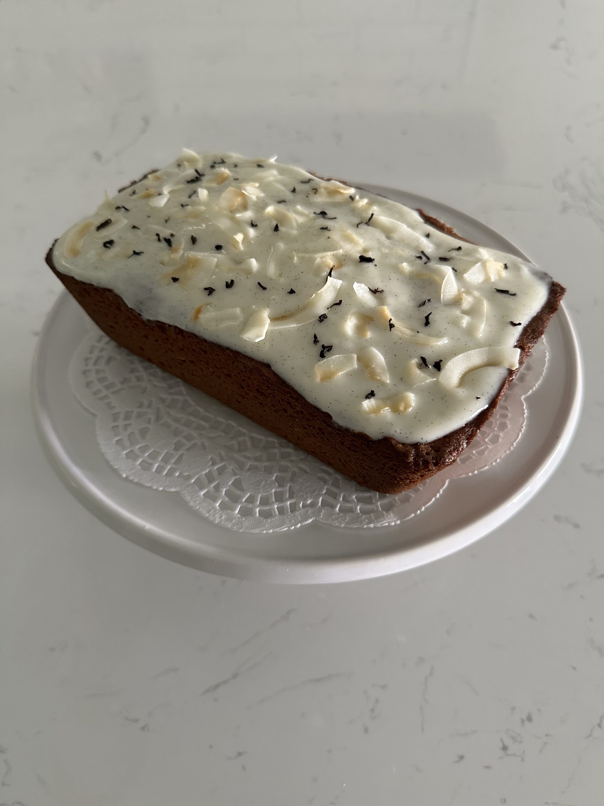 earl gray coconut pound cake with a sour cream glaze decorated with earl gray tea leaves and toasted coconut chips. 